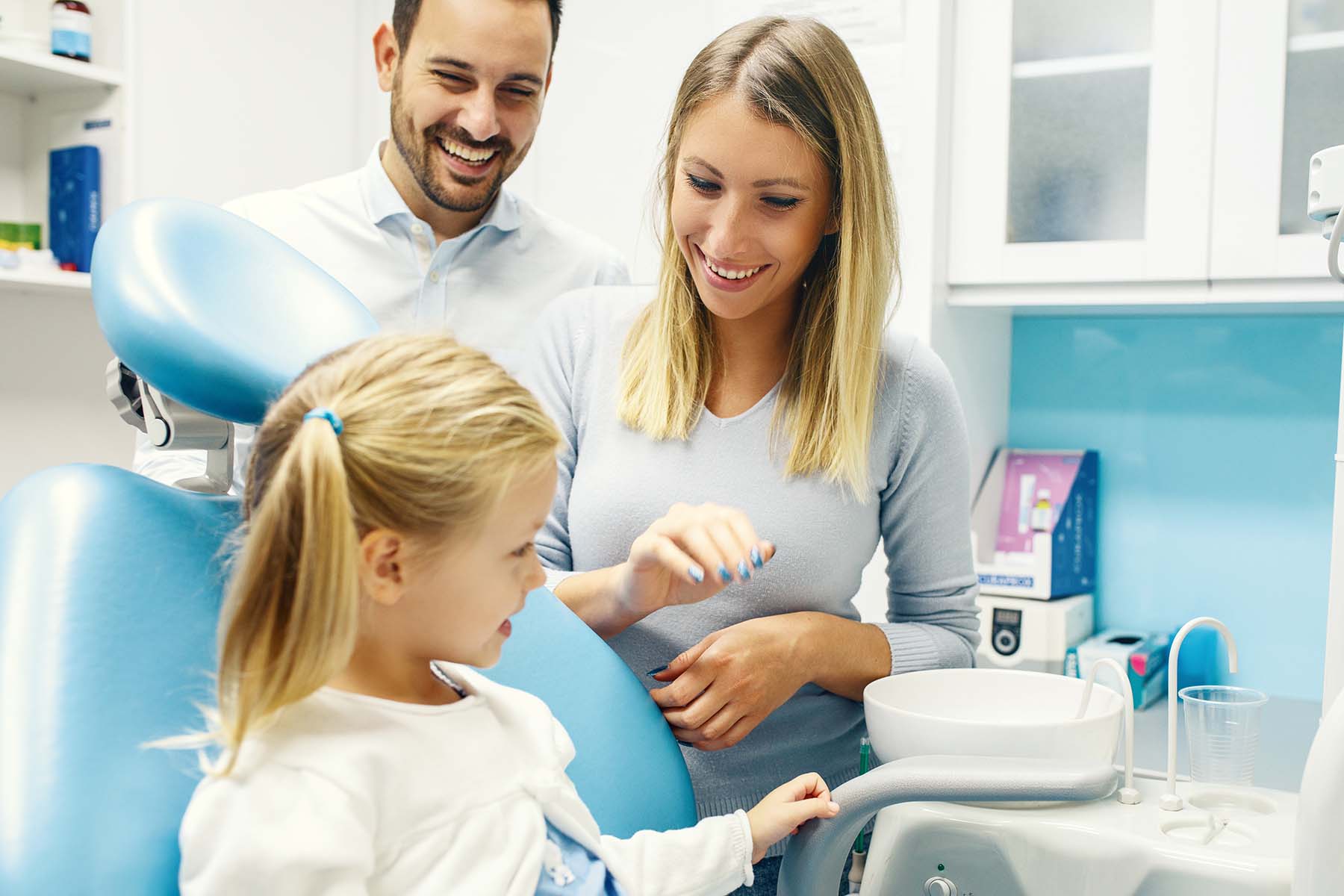 Dentist treating cute blonde child in his surgery.